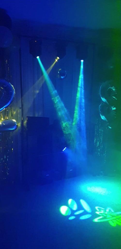 Scena oświetlona reflektorami w kolorach niebieskim i zielonym, z balonami i dekoracjami w tle.