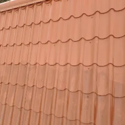 Czerwono-brązowa blachodach&oacute;wka ułożona na dachu w Pułtusku, widoczne ślady po deszczu.