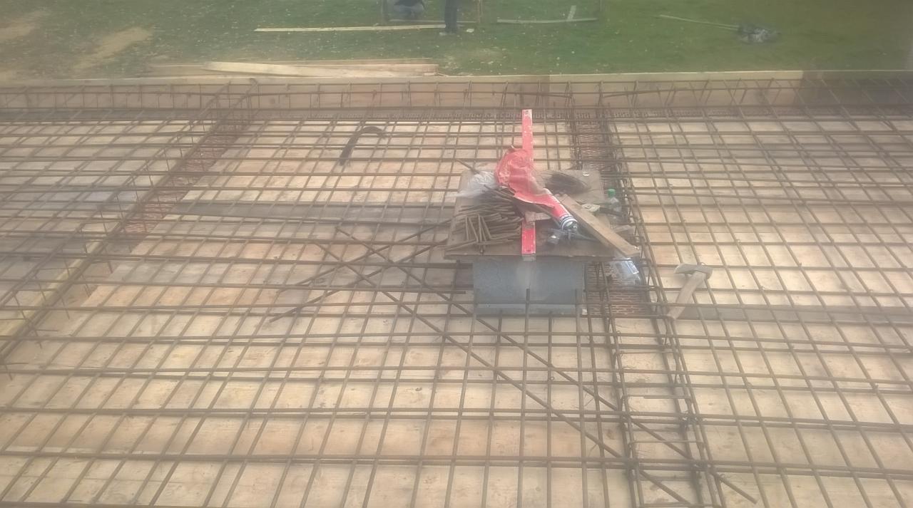 Siatka zbrojeniowa ułożona na deskowaniu, przygotowana do zalania betonem; widoczne narzędzia i materiały budowlane w tle.