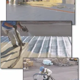 Aplikacja warstwy izolacyjnej na płaski dach za pomocą specjalistycznego sprzętu natryskowego. Widoczne białe wykończenie dachu, przewody doprowadzające materiał i pracownik w kasku ochronnym...