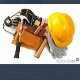 Pas z narzędziami, młotek, miarka, kombinerki, poziomica, żółty kask i szare rękawice robocze na białym tle.