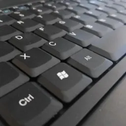 Zbliżenie na klawiaturę laptopa z widocznymi klawiszami Z, S, X, C, V, Alt, Ctrl i klawiszem Windows, z delikatnym załamaniem światła na powierzchni klawiszy.