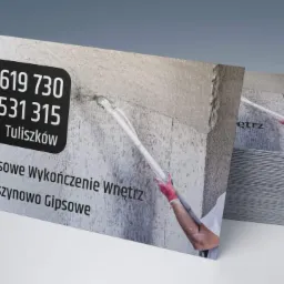 Stos wizytówek firmy budowlanej prezentujących tynkowanie maszynowe gipsowe oraz kompleksowe wykończenie wnętrz, widoczne numery telefonów i nazwa miejscowości Tuliszków. Na wizytówce w tle...