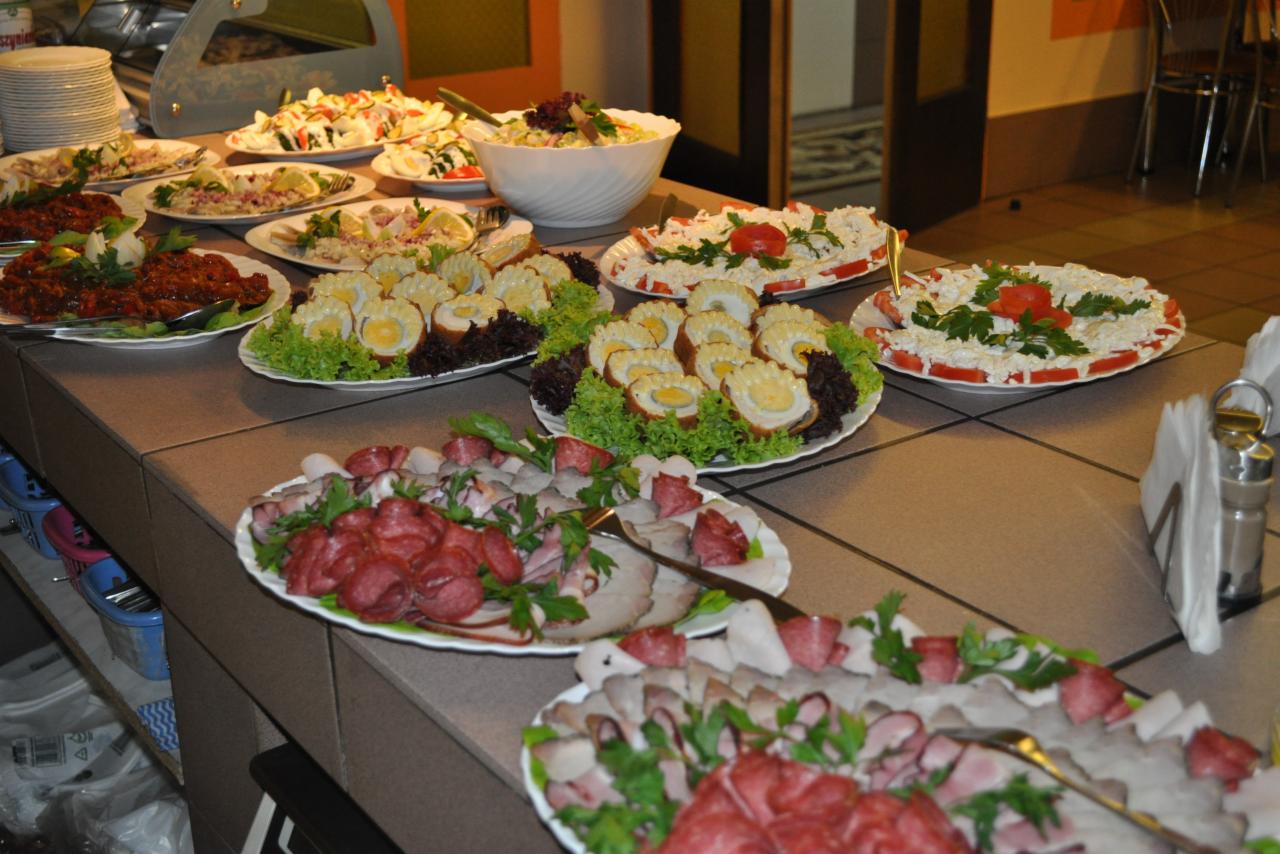 Bufet z różnorodnymi daniami: sałatki warzywne, jajka w galarecie, wędliny na paterach, przygotowany na przyjęcie.