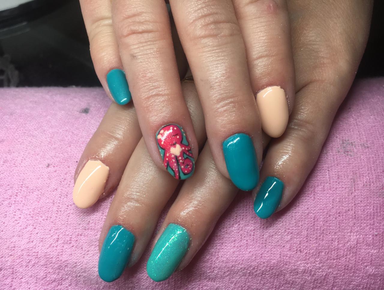 Dłonie z pomalowanymi paznokciami: turkusowymi, brzoskwiniowymi i jednym paznokciem z motywem czerwonego ośmiornicy na turkusowym tle.