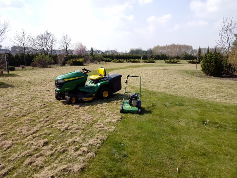 Dwie kosiarki (traktorek i kosiarka spalinowa) na trawniku z widocznymi śladami koszenia i resztkami trawy, w tle zadbane krzewy i drzewa.