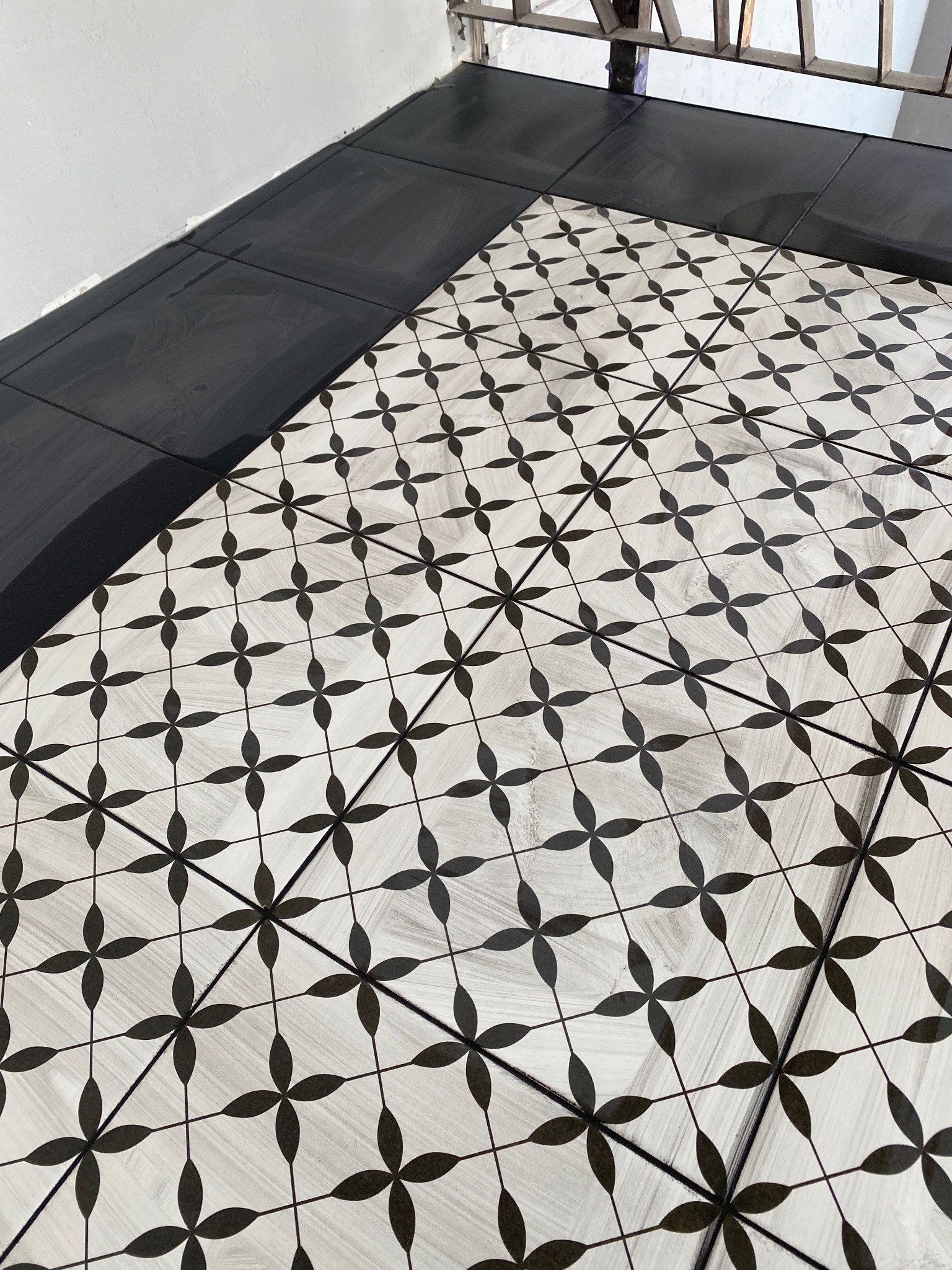 Ułożona podłoga z płytek w Szczecinie, z czarnym obramowaniem i wzorem w czarno-białe kwiaty, widok z góry.