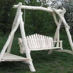 Drewniana huśtawka ogrodowa z siedziskiem wykonanym z pionowych listew, zawieszona na łańcuchach, z dodatkową półką z boku, wykonana z surowego drewna.