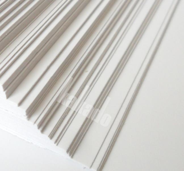 Stos białych, gładkich arkuszy papieru ułożonych równo, widoczne krawędzie i faktura papieru pod delikatnym kątem.