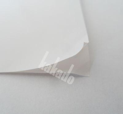 Stos arkuszy białego papieru z delikatnie podwiniętym rogiem, widoczne subtelne cieniowanie i tekstura.