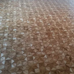 Parkiet ułożony w geometryczny wzór gwiazd, z wyraźnymi słojami drewna i delikatnym połyskiem lakieru.