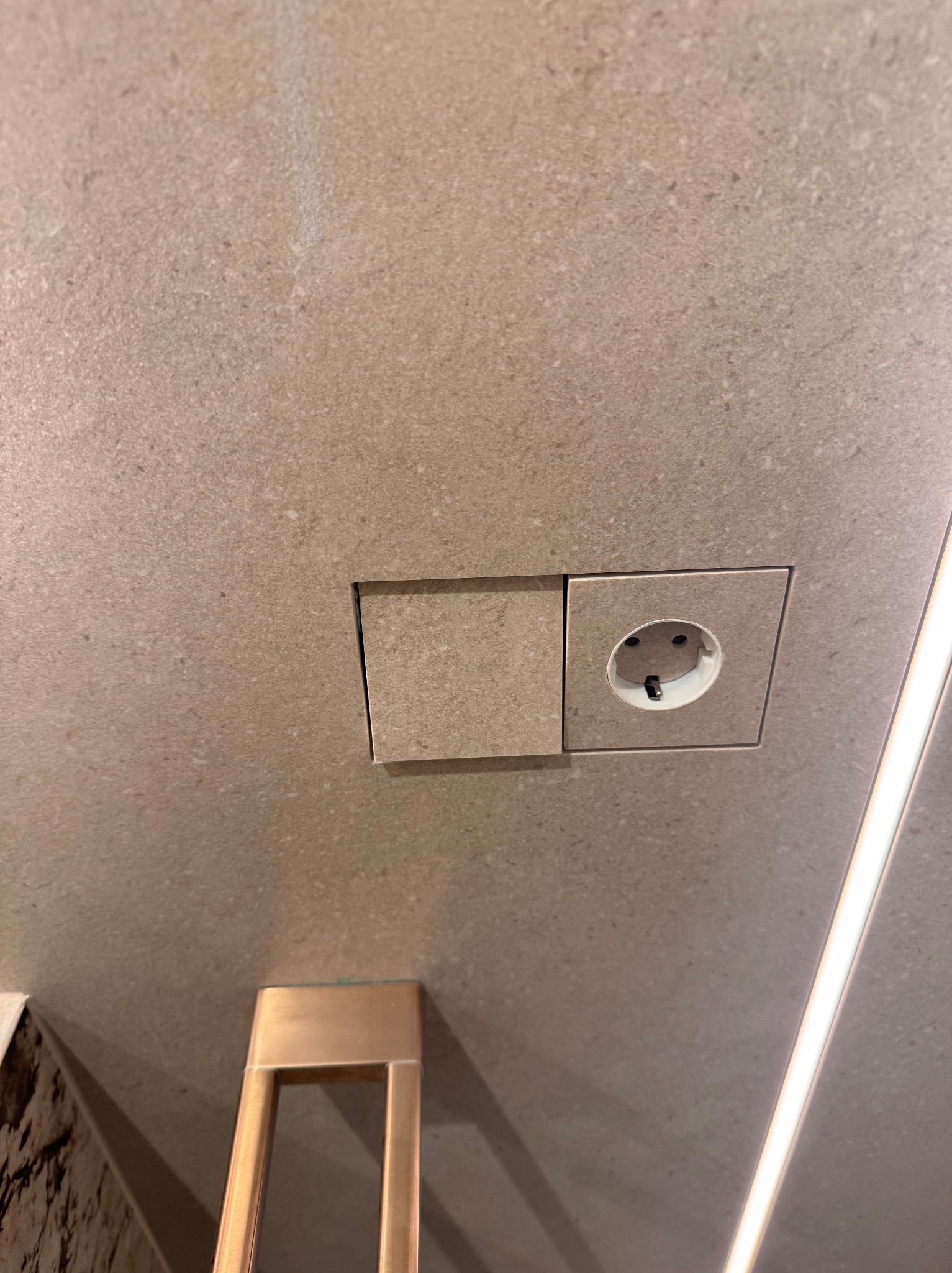 Gniazdko elektryczne zlicowane z płytkami w łazience w Krakowie. Estetyczne wykończenie ściany z ukrytą puszką. Minimalistyczny design i precyzyjny montaż.