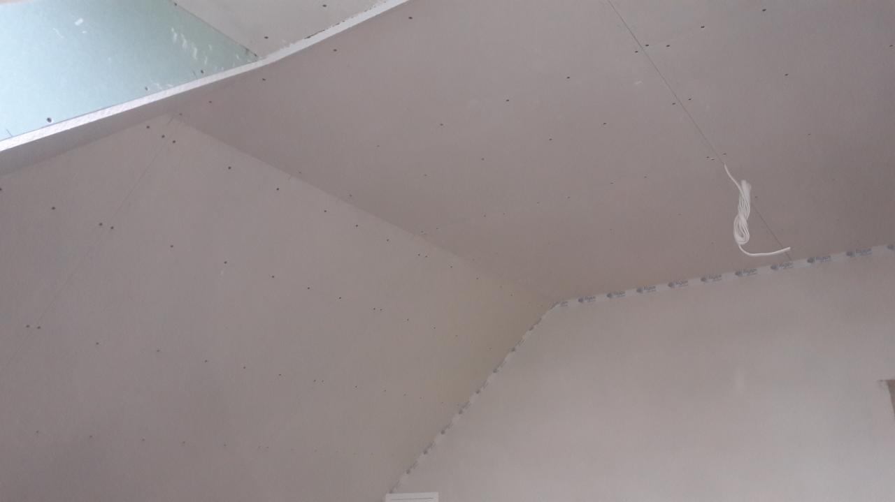 Sufit pod skosem z zamontowaną płytą gipsowo-kartonową, widoczne ślady po wkrętach i fragment przewodu elektrycznego.