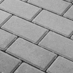 Szare, prostokątne elementy ułożone w jodełkę, tworzące powierzchnię. Widoczne delikatne spoiny między poszczególnymi elementami.