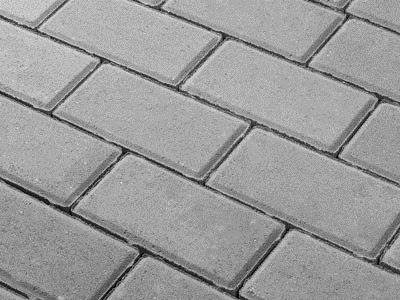 Szare, prostokątne elementy ułożone w jodełkę, tworzące powierzchnię. Widoczne delikatne spoiny między poszczególnymi elementami.