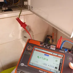 Pomiar rezystancji uziemienia miernikiem Sonel MPI-540 w rozdzielnicy elektrycznej, widoczny zacisk pomiarowy na przewodzie uziemiającym.