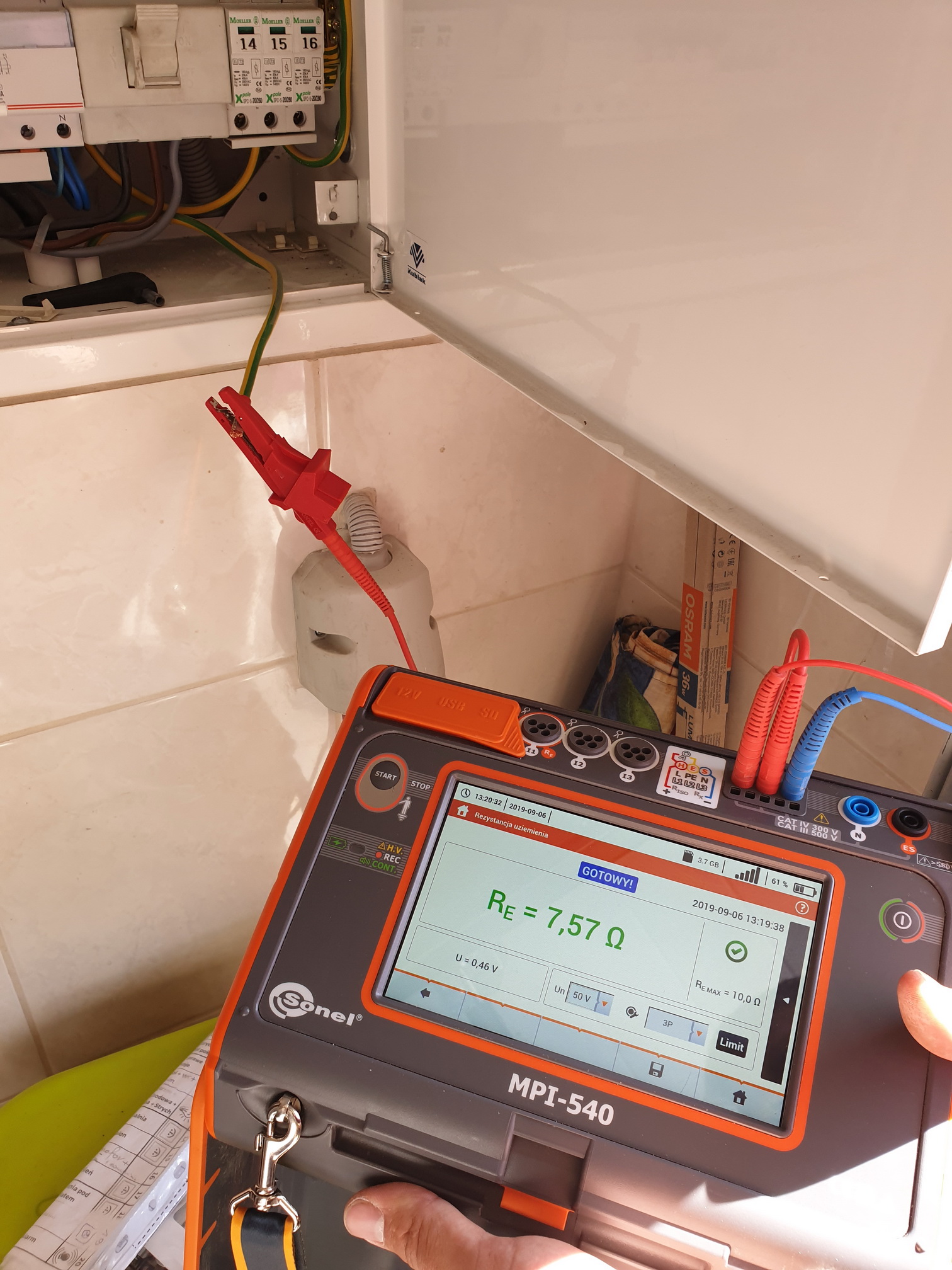 Pomiar rezystancji uziemienia miernikiem Sonel MPI-540 w rozdzielnicy elektrycznej, widoczny zacisk pomiarowy na przewodzie uziemiającym.