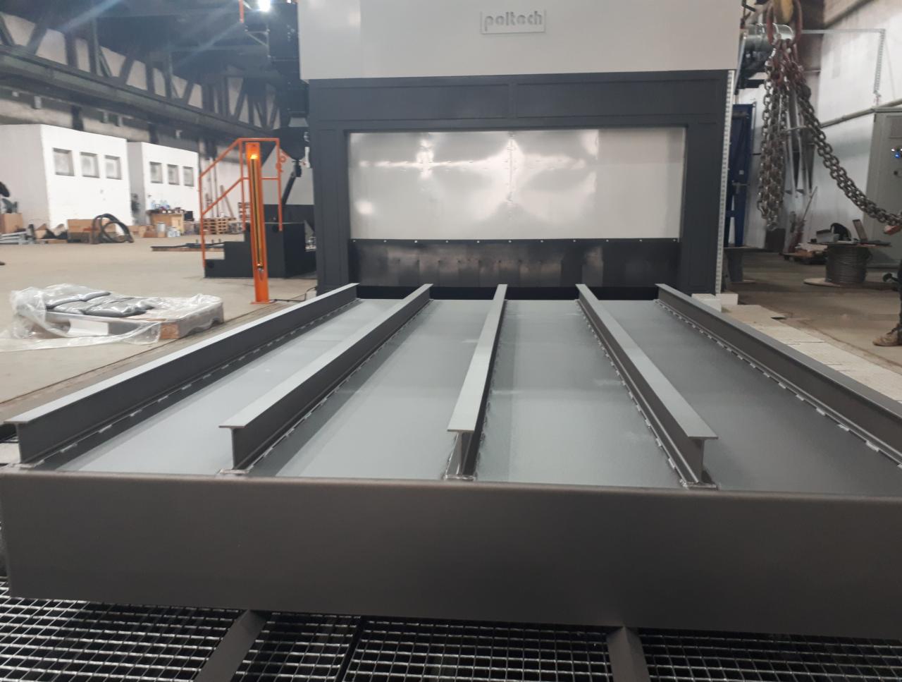 Wnętrze komory do obróbki strumieniowo-ściernej, widoczne stalowe profile wewnątrz, szara powierzchnia robocza i elementy konstrukcyjne komory.