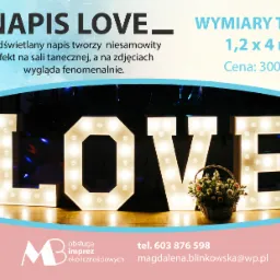 Świecący napis LOVE z żarówkami, ustawiony na parkiecie z koszem kwiatów pośrodku, w tle dekoracje sali tanecznej, ujęcie z bliska.