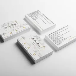 Stosy wizytówek z marmurkowym tłem i złotymi akcentami, logo 'La Love Beauty' i danymi kontaktowymi, ułożone na białym tle.