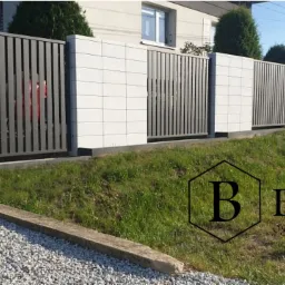 Nowoczesne ogrodzenie panelowe z betonowymi słupkami, widok z zewnątrz na tle domu jednorodzinnego i trawnika, z logo firmy w prawym dolnym rogu.