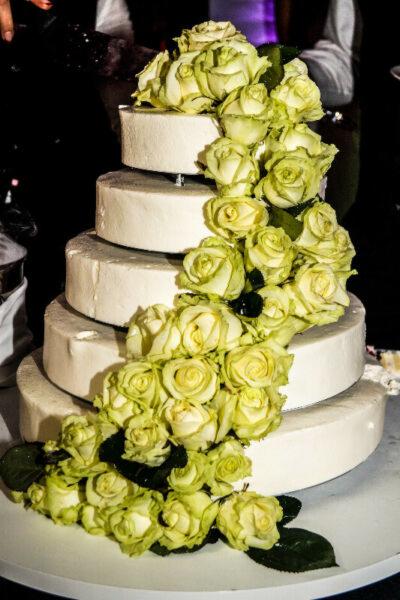 Czteropiętrowy tort weselny z białego kremu, udekorowany kaskadą bladozielonych róż.