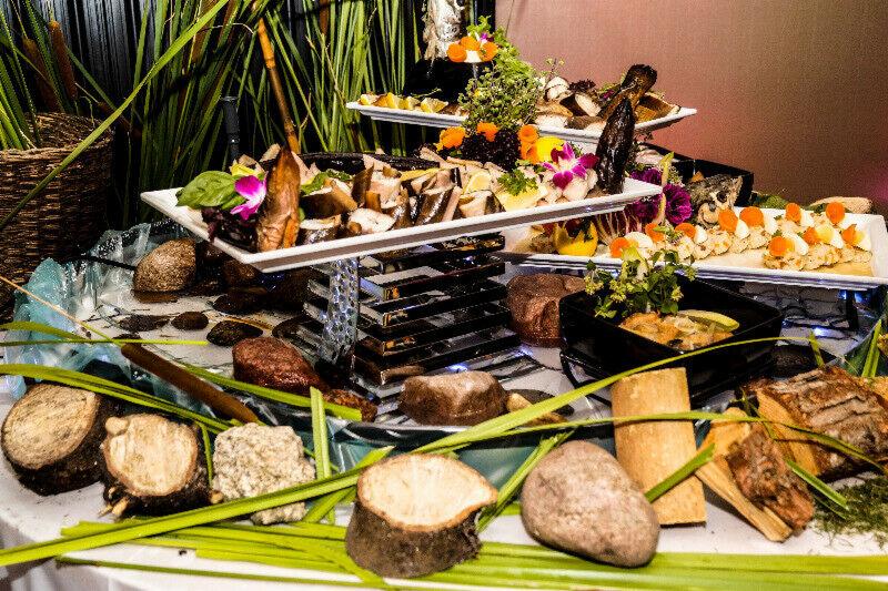 Dekoracyjny bufet z wędzoną rybą, kwiatami i elementami drewna na kilku poziomach.