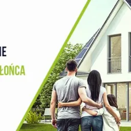 Rodzina stojąca przed nowoczesnym domem jednorodzinnym z panelami słonecznymi na dachu, widoczne logo firmy PVG i hasło 'Elektrownie Słoneczne. Darmowa energia ze słońca. Odbierz 5000zł...