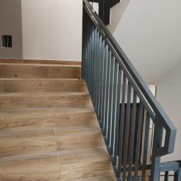 Badura Welding - Szare metalowe barierki schodowe z pionowymi prętami na drewnopodobnych schodach w Aleksandrowie Kujawskim.