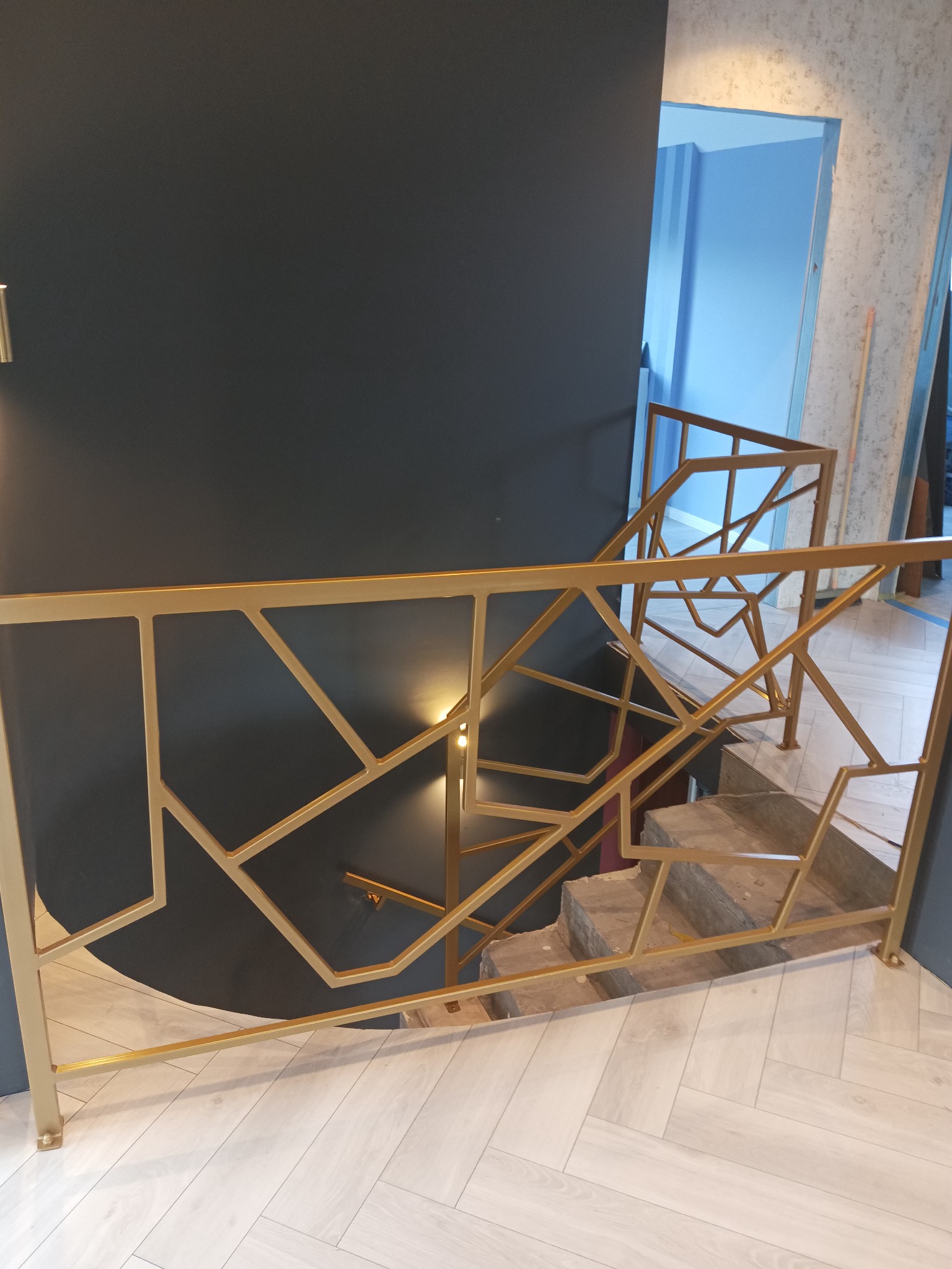 Złota balustrada schodowa z geometrycznym wzorem w Będzinie. Nowoczesny design, eleganckie wykończenie. Widok z góry na schody.