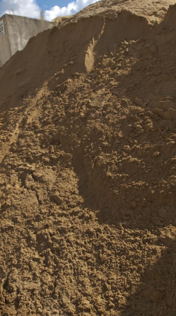 Góra piasku budowlanego z wyraźnymi śladami opon w tle, fragment betonowej ściany z numerem 28 w lewym górnym rogu.