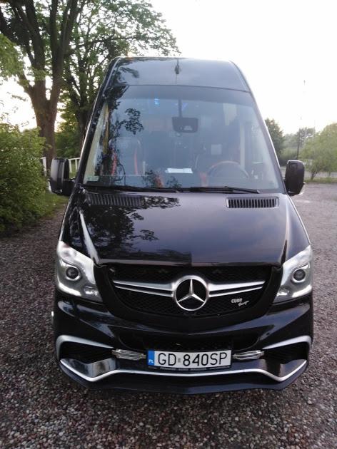 Czarny, luksusowy bus Mercedes-Benz Sprinter z chromowanymi akcentami, widok z przodu, tablica rejestracyjna GD 840SP, na tle drzew i szarej nawierzchni.