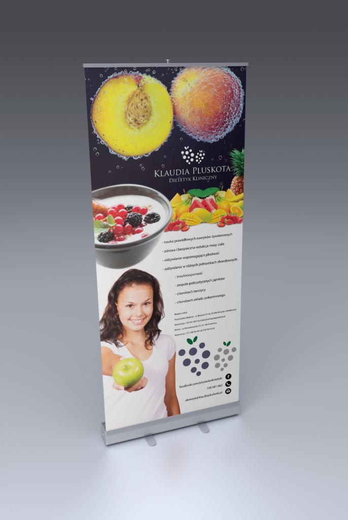 Roll-up reklamowy dietetyka klinicznego Klaudii Pluskoty, z grafiką przekroju brzoskwini, miseczki z owocami i uśmiechniętej kobiety trzymającej zielone jabłko.
