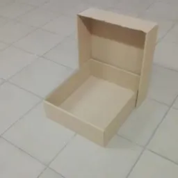 Otwarty, beżowy karton na podłodze z jasnych płytek, widoczny z góry pod kątem.