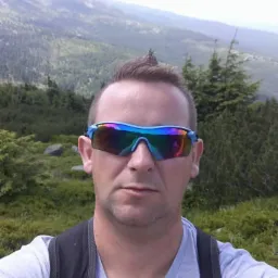 Mężczyzna w okularach przeciwsłonecznych na tle górskim w Skępem. Widok zza ramienia, zieleń i szczyty w oddali. Selfie.