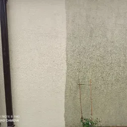 Fragment elewacji budynku z widoczną różnicą w kolorze po lewej i prawej stronie, prawdopodobnie po czyszczeniu. Dwie rury spustowe po lewej stronie. Na dole kadru widoczny znak wodny aparatu.