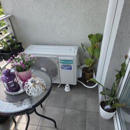 Cold ice klim - Biały klimatyzator Hisense na balkonie z kwiatami, lampionem i roślinami doniczkowymi, tworzący przytulny kącik.