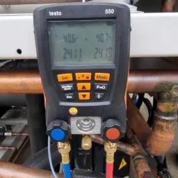 Pomiar parametrów klimatyzacji w Bydgoszczy za pomocą urządzenia Testo 550, z widocznymi przewodami i rurami instalacji. Kontrola szczelności.