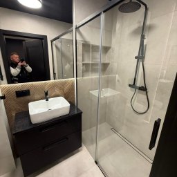 KARLITO WYKOŃCZENIA WNĘTRZ ADRIAN GŁUSZCZAK - Nowoczesna łazienka z kabiną prysznicową typu walk-in i umywalką nablatową w Gorzowie Wielkopolskim. Czarna armatura i drewnopodobna ściana dodają elegancji.