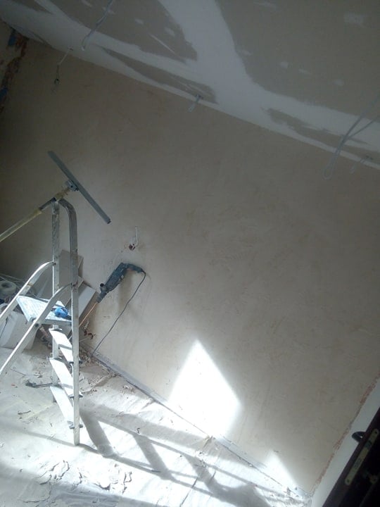 Ściana w trakcie wykańczania w Balin, widoczna drabina, narzędzia i fragment sufitu z wystającymi kablami.