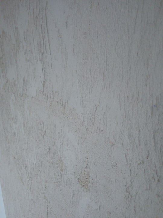 Szara ściana z wyraźną fakturą imitującą przecierki i nierówności w pionie.