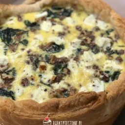 Quiche ze szpinakiem, serem feta i orzechami włoskimi w kruchym cieście, widoczne logo firmy na dole zdjęcia.