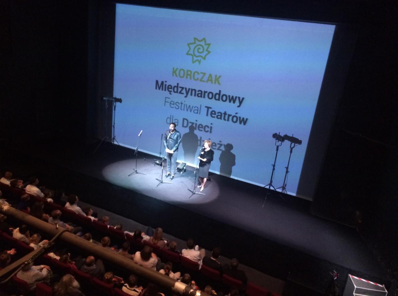 Prezentacja na scenie podczas Międzynarodowego Festiwalu Teatrów dla Dzieci Korczak, widok z góry na publiczność siedzącą w czerwonych fotelach.