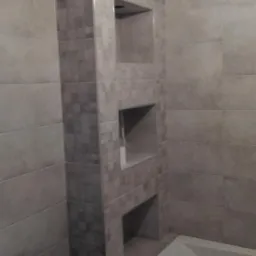 Wykończona łazienka z szaro-beżowymi płytkami, wnękami w zabudowie i fragmentem wanny.