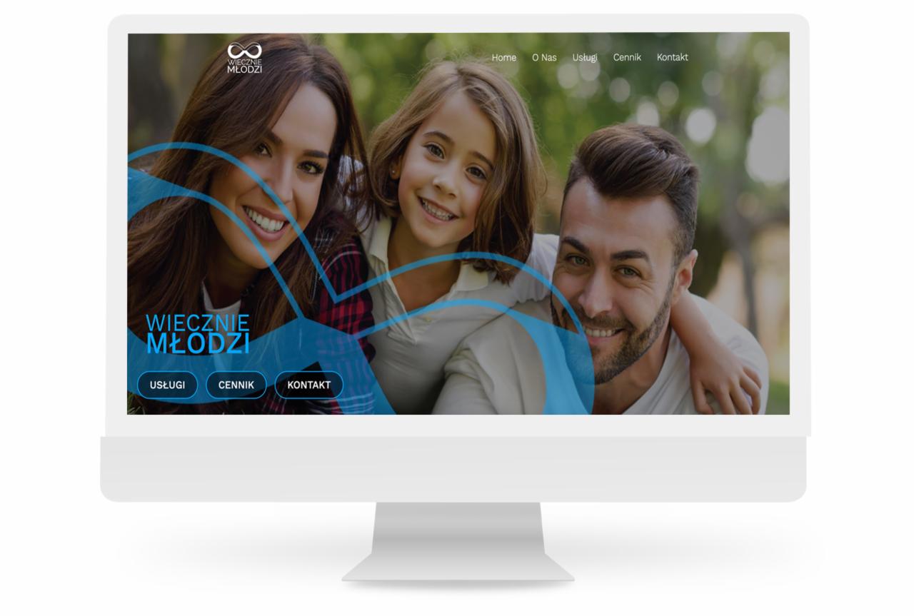 Ekran monitora wyświetlający stronę internetową z uśmiechniętą rodziną (matka, córka, ojciec) i logo 'Wiecznie Młodzi' w lewym górnym rogu.