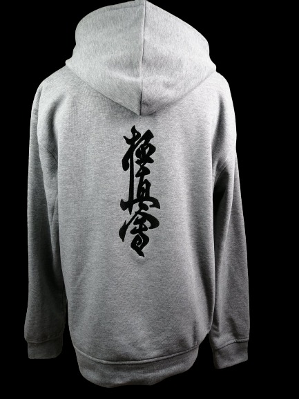 Szara bluza z kapturem, widok z tyłu, z wyhaftowanym czarnym znakiem Kyokushin Karate na plecach, na czarnym tle.