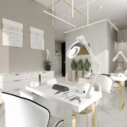 Wnętrze salonu kosmetycznego z dwoma stanowiskami do manicure. Białe meble z akcentami złota, rośliny doniczkowe, lampy oświetleniowe. Stonowana kolorystyka.