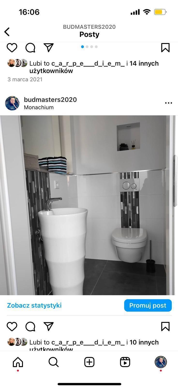 Nowoczesna łazienka w bieli i szarości. Umywalka kolumnowa, podwieszana toaleta z mozaiką. Minimalistyczny design z wnęką dekoracyjną. Widok z poziomu podłogi.