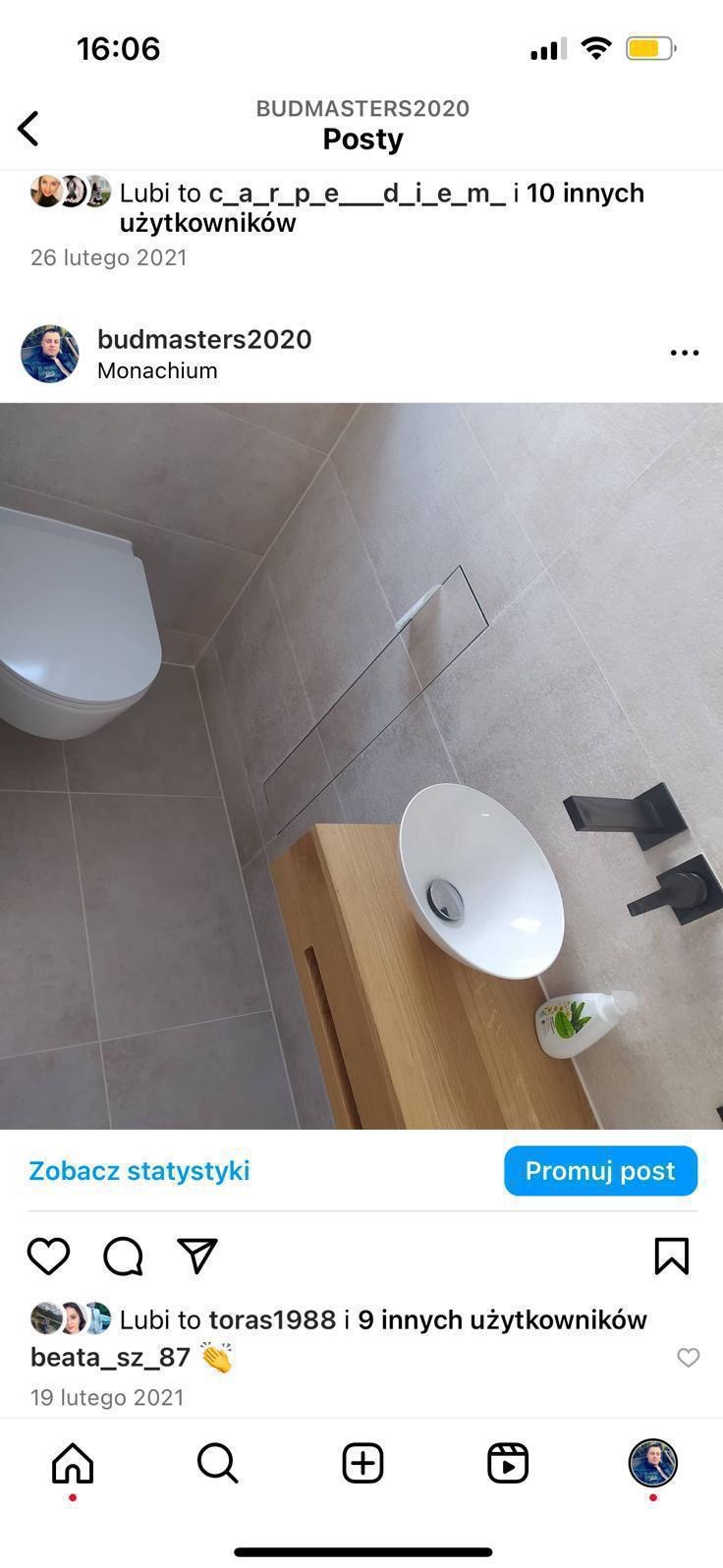 Minimalistyczna łazienka z umywalką nablatową na drewnianym blacie, odpływem liniowym i podwieszaną toaletą. Szare płytki i czarna armatura.