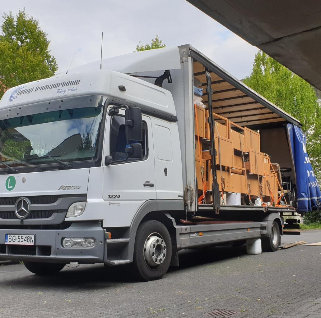 Ciężarówka Mercedes Atego 1224 z otwartą naczepą, załadowana meblami zabezpieczonymi pasami, widziana w Żernicy pod wiaduktem.